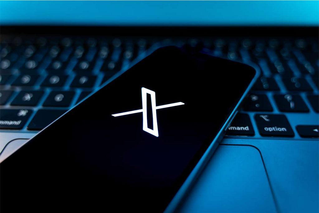 logo social X su schermo smartphone appoggiato a tastiera pc