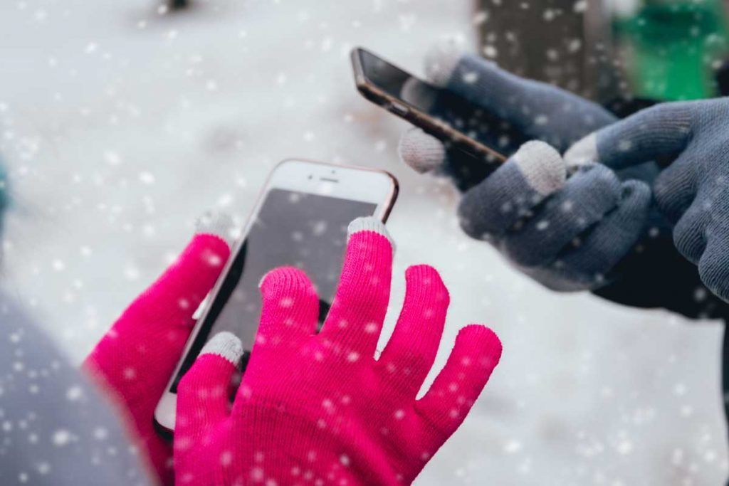 coppia utilizza smartphone con guanti sotto la neve