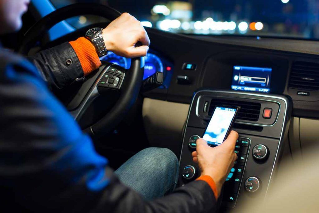 uomo usa smartphone in auto mentre guida