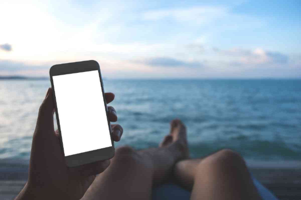 Persona utilizza il telefono al mare