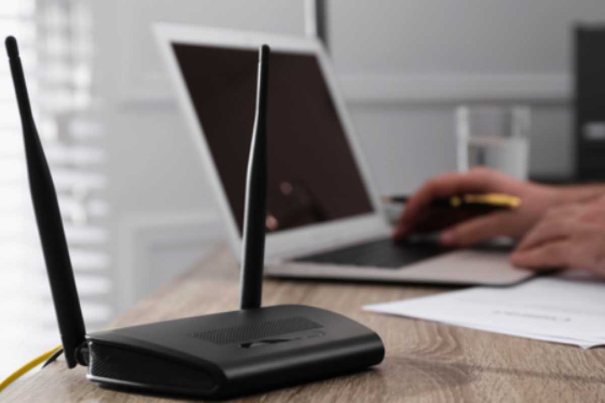 Persona tiene il router del Wi-Fi sulla scrivania mentre lavora