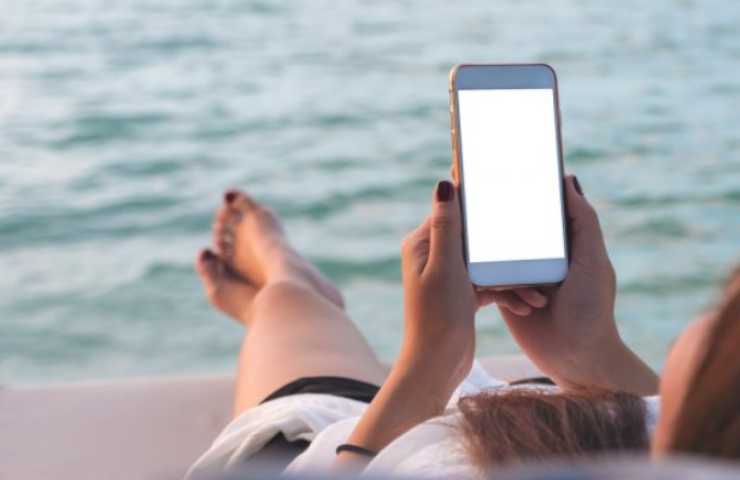 Ragazza utilizza l'iPhone al mare