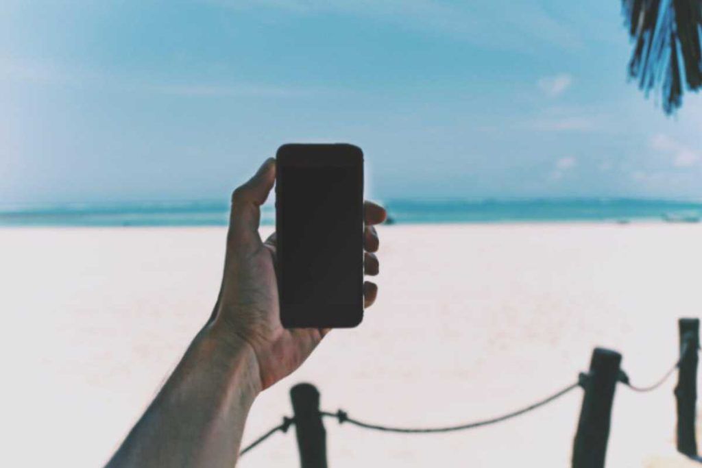 Persona utilizza lo smartphone in spiaggia