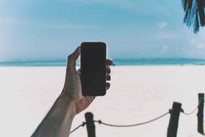 Persona utilizza lo smartphone in spiaggia